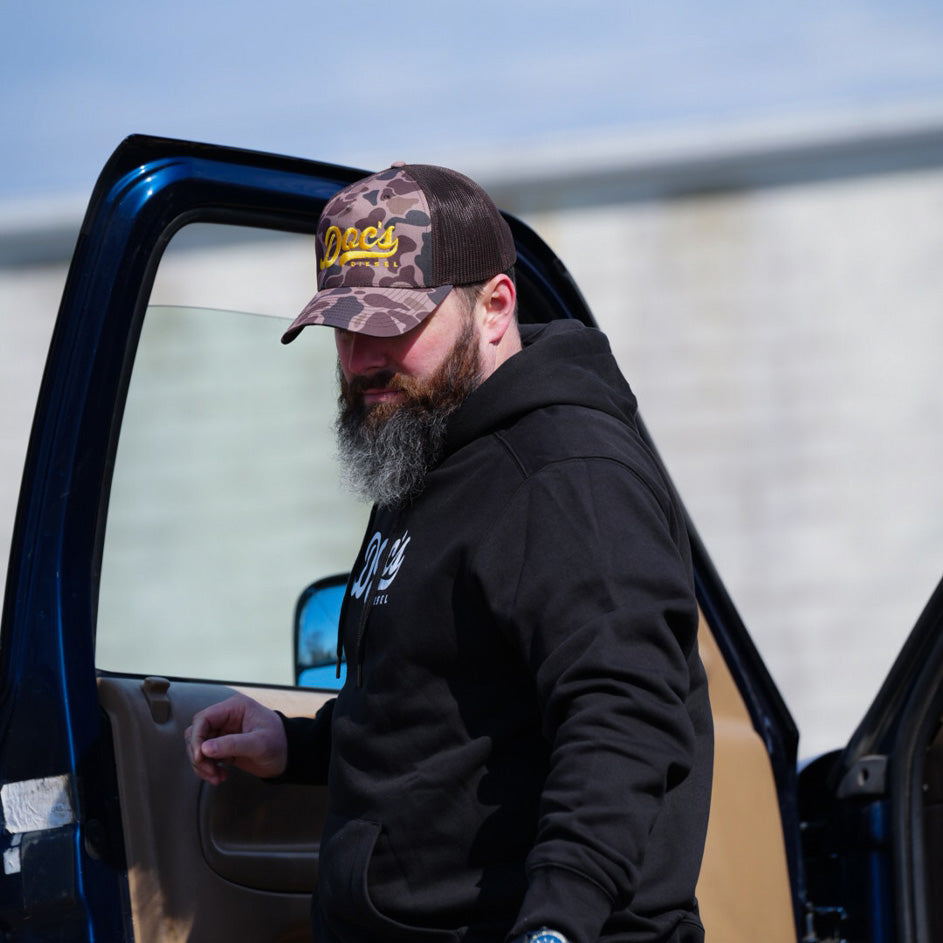 Doc's Diesel Camo Trucker Hat on man wearing a black Doc's Diesel Hoodie